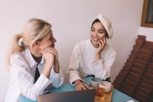 cheerful hipster girls with netbook device discussing idea for copywriting
